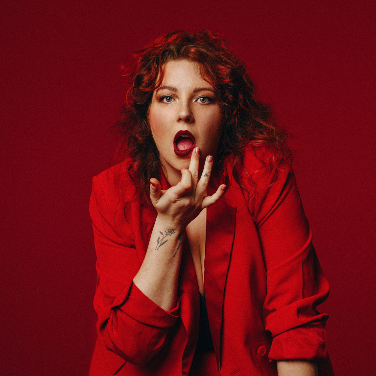 jessie nixon wearing a red suit in front of a red background